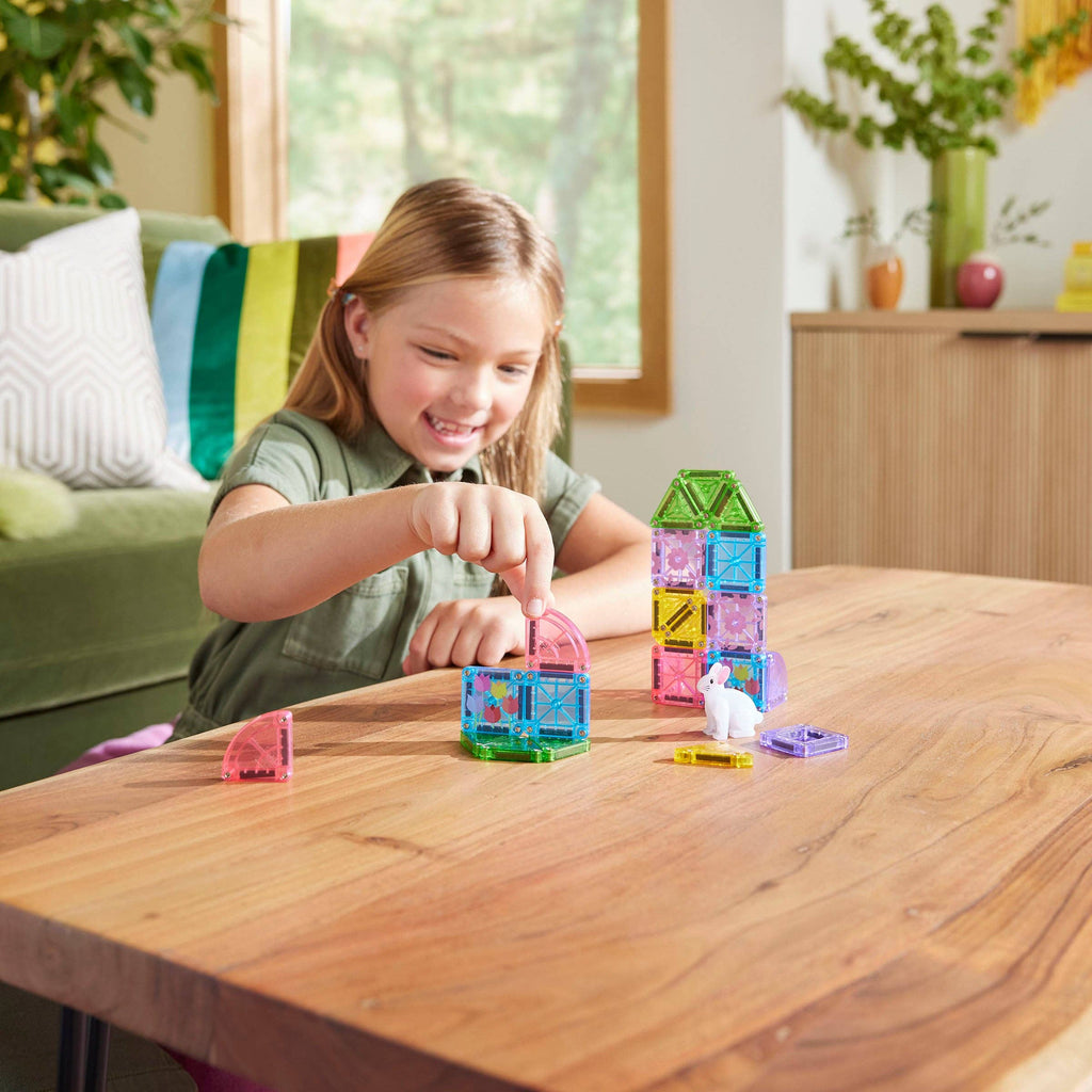Girl using creative play and her STEM skills to build a shelter for her microMAGs Spring Garden travel set.